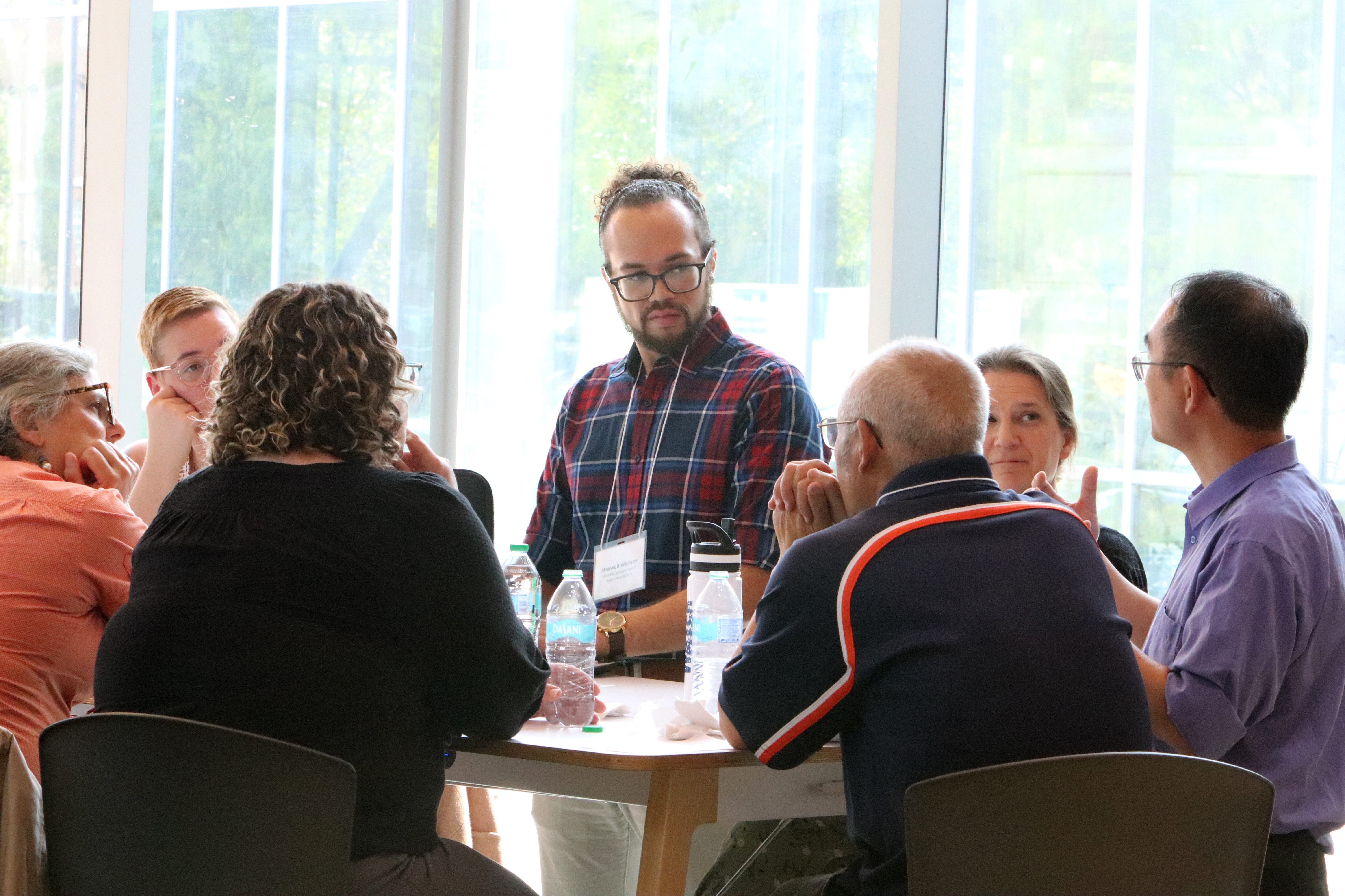 IHSI staff member facilitates discussion among a group of 6 colleagues sitting at a round table